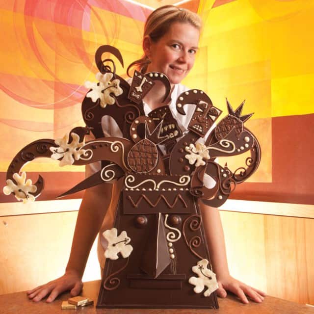 Emily McCracken standing behind a chocolate tiki mask sculpture